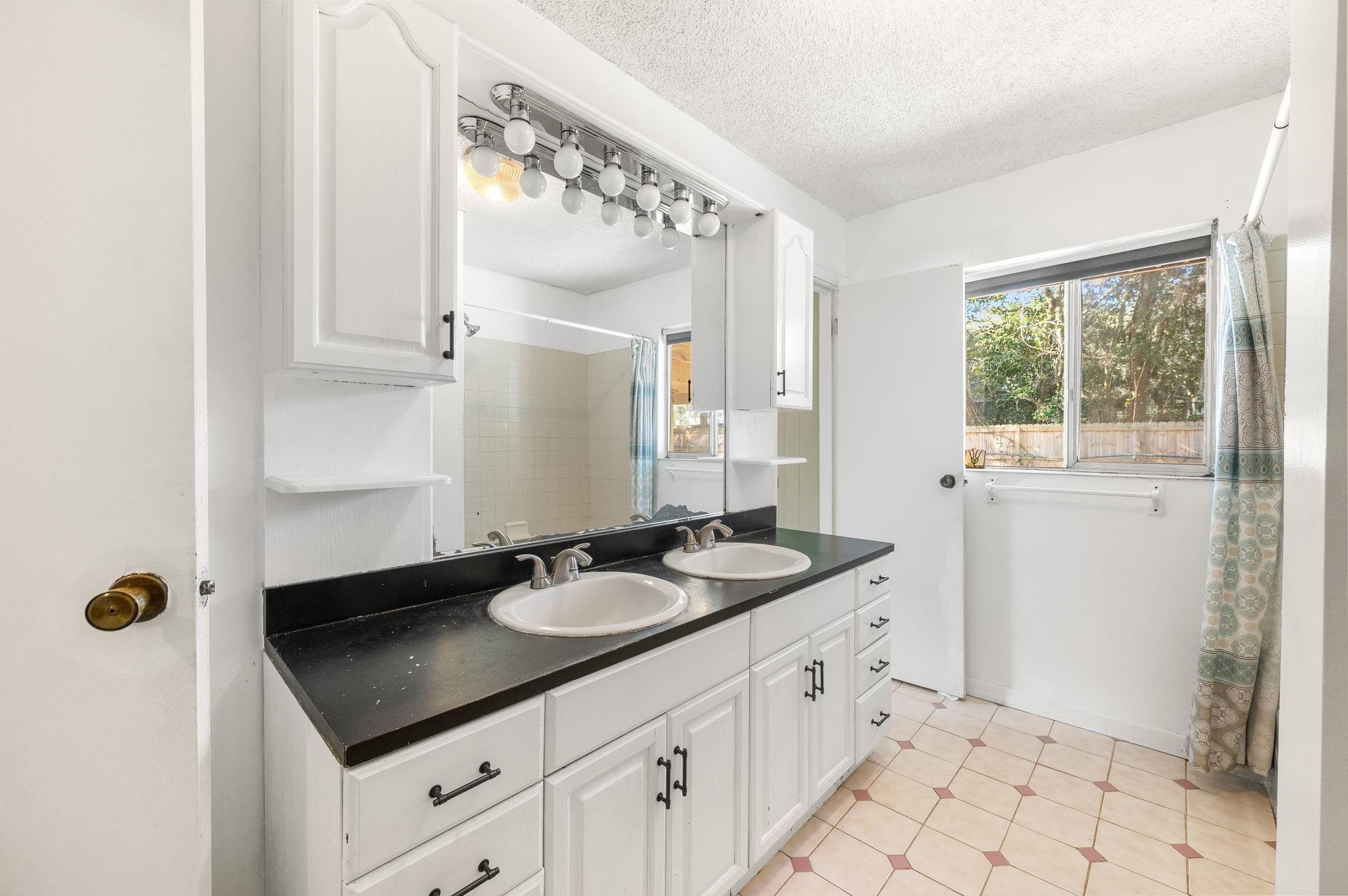 414 Jasmine Road St. Augustine, FL 32086 - Photo 14 of 30 a bathroom with a granite countertop sink a mirror and a shower
