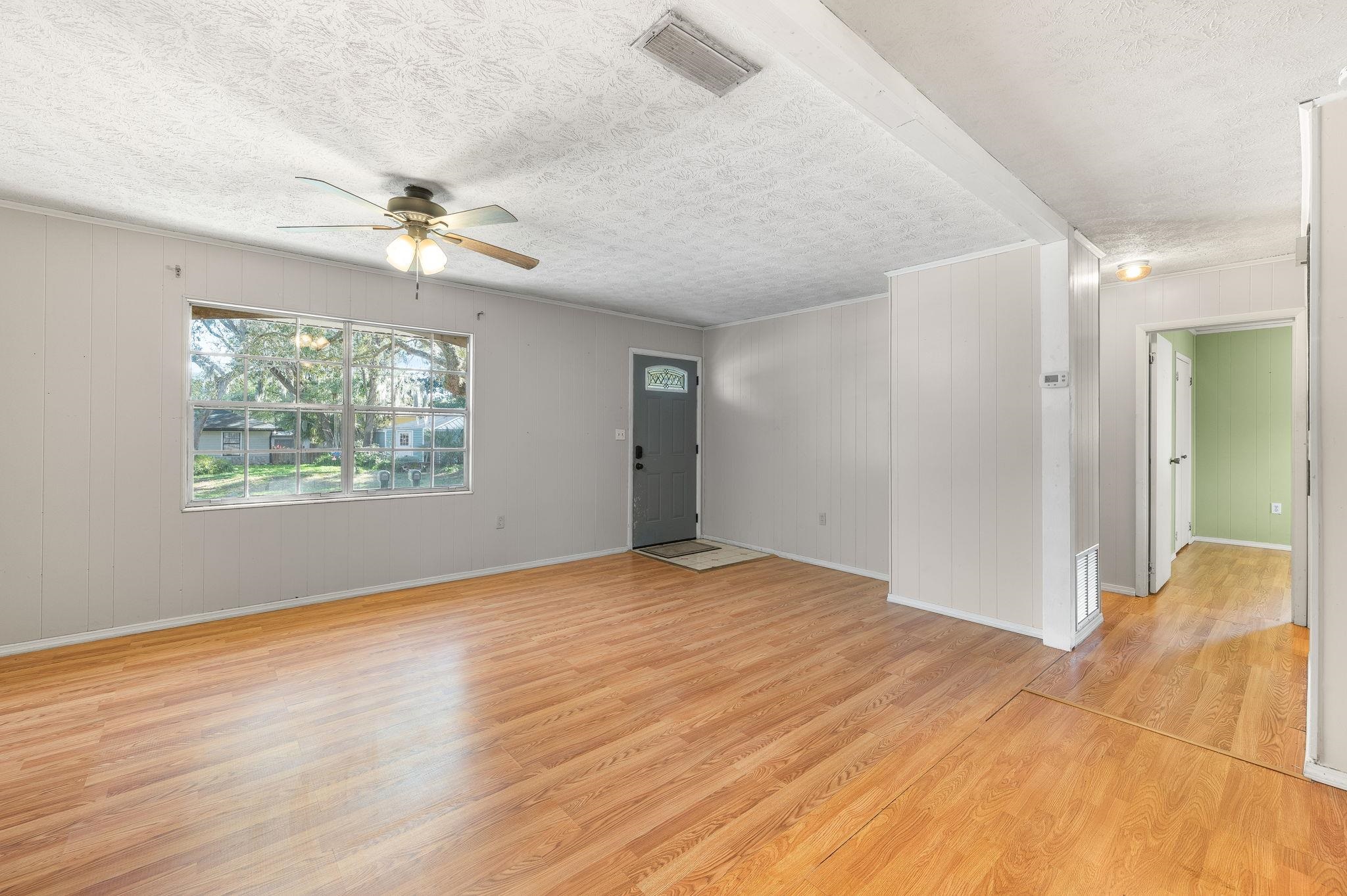 414 Jasmine Road St. Augustine, FL 32086 - Photo 7 of 30 an empty room with wooden floor chandelier fan and windows