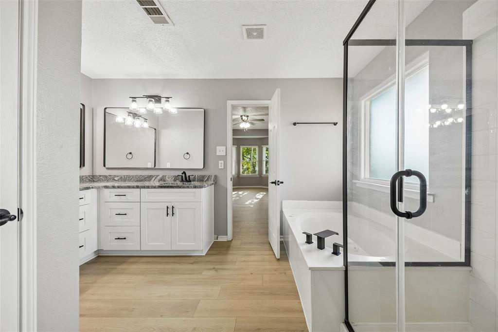 753 Summerfield Drive Allen, TX 75002 - Photo 25 of 40 Contemporary bathroom featuring a spacious walk-in shower with a glass enclosure, a separate soaking tub with matte black fixtures, and a dual vanity with white cabinetry and dark countertops