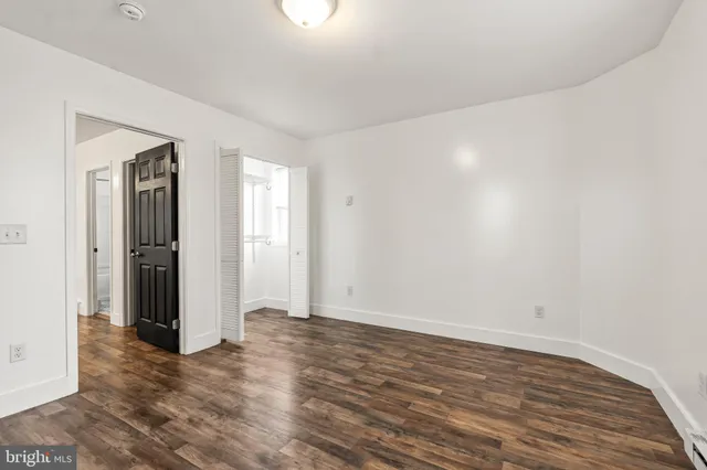 a view of an empty room with wooden floor and closet