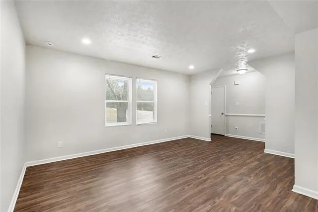 an empty room with wooden floor cabinet and windows