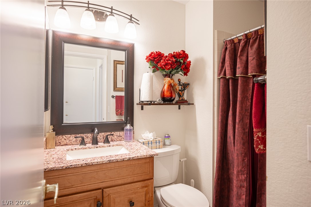 718 Rusty Spur Drive Henderson, NV 89014 - Photo 32 of 50 Elegant granite counters and a warm wood vanity create a welcoming bathroom space.
