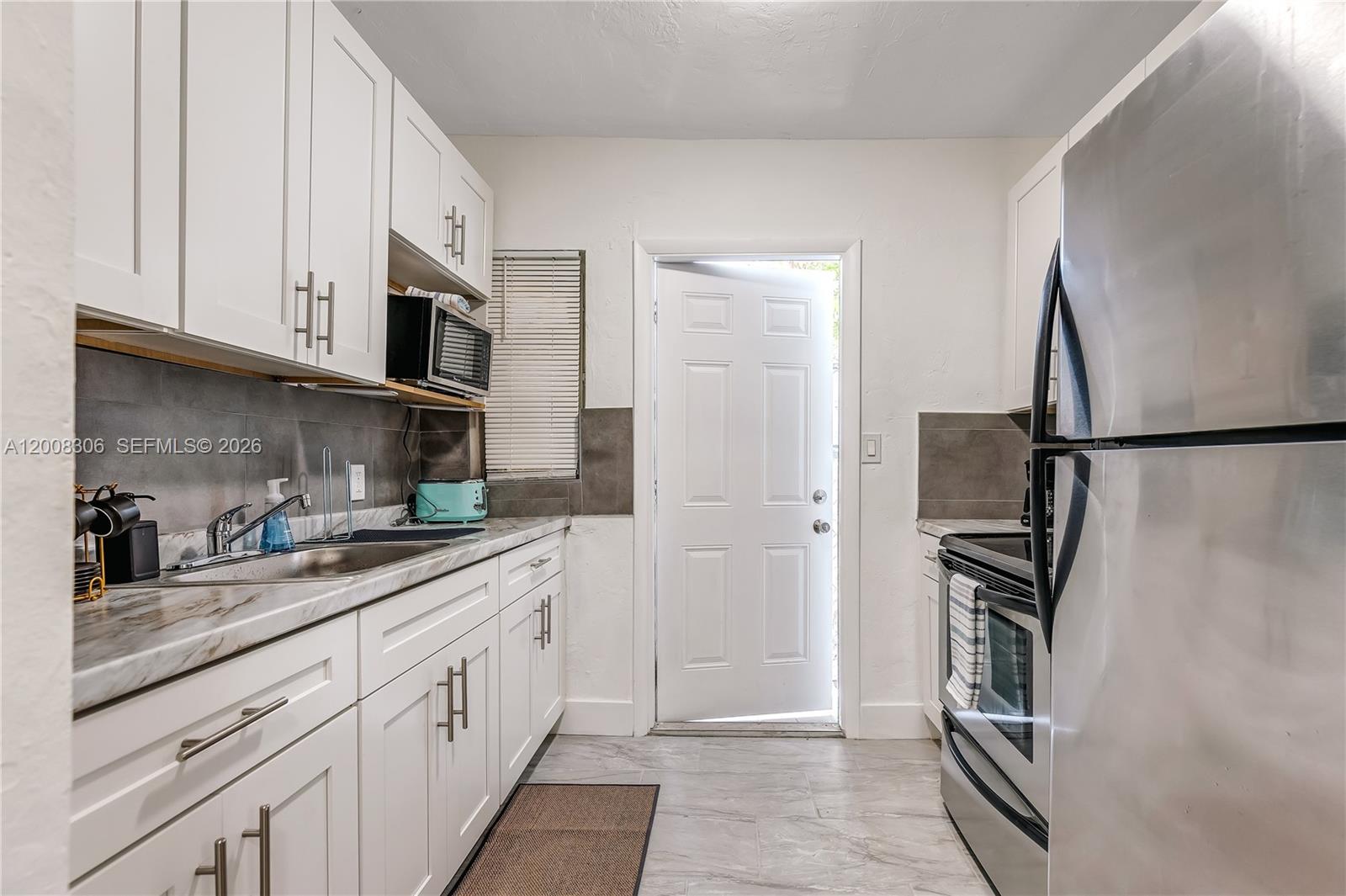 327 Northeast 55th Street, Unit 2 Miami, FL 33137 - Photo 6 of 14 a kitchen with stainless steel appliances granite countertop a refrigerator and a stove top oven