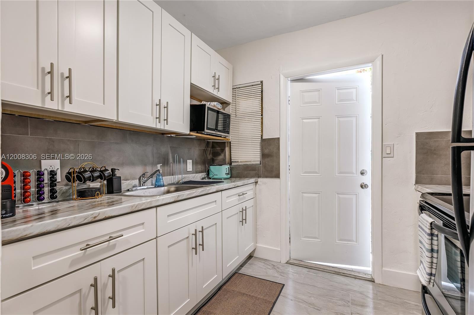 327 Northeast 55th Street, Unit 2 Miami, FL 33137 - Photo 7 of 14 a kitchen with stainless steel appliances granite countertop white cabinets and refrigerator