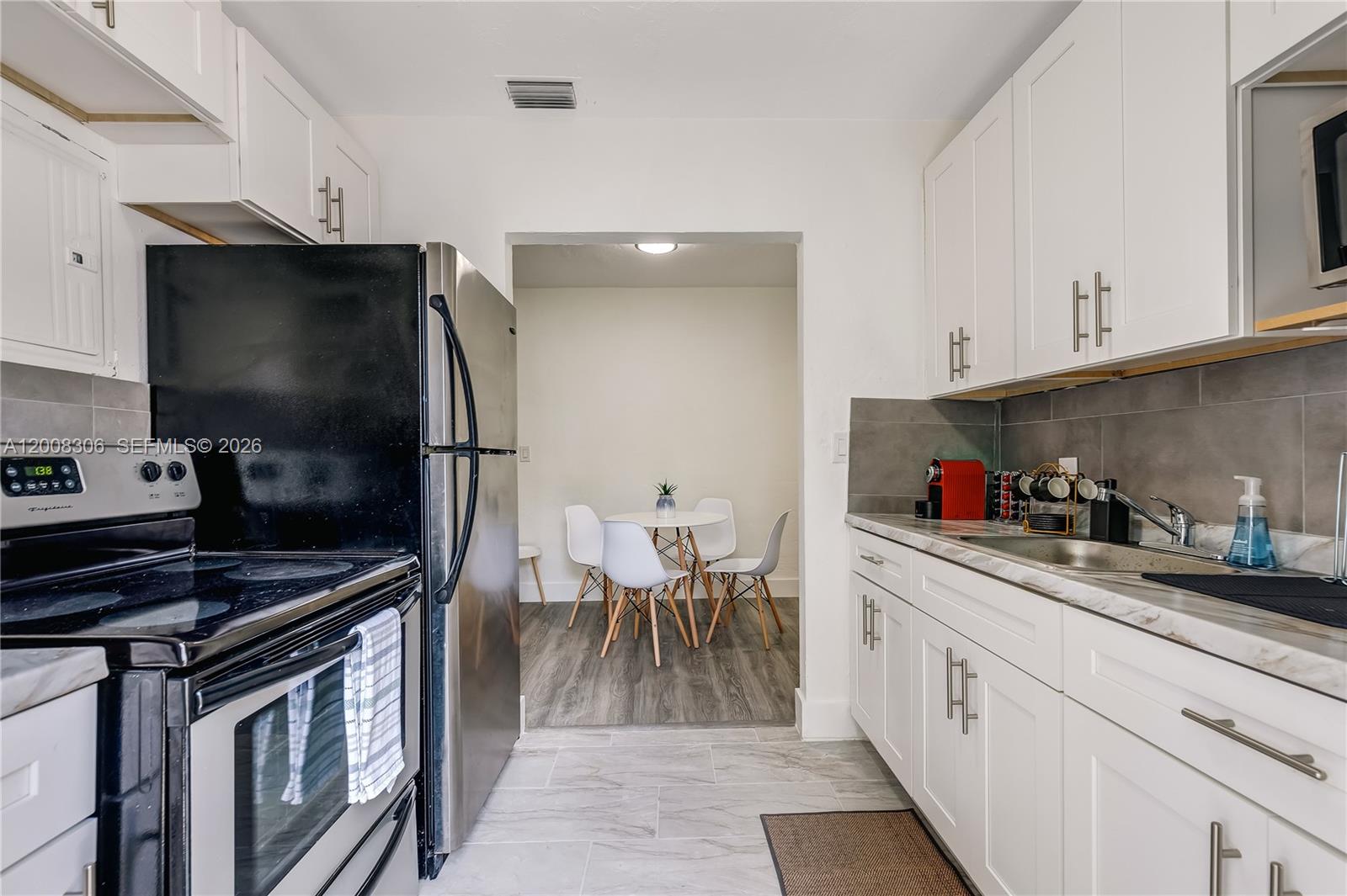 327 Northeast 55th Street, Unit 2 Miami, FL 33137 - Photo 8 of 14 a kitchen with granite countertop a sink stove and cabinets