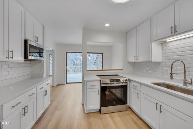 a kitchen with cabinets wooden floor and stainless steel appliances