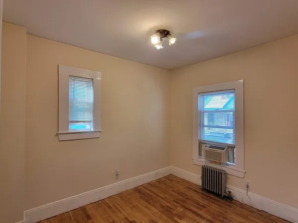 an empty room with wooden floor cabinet and windows