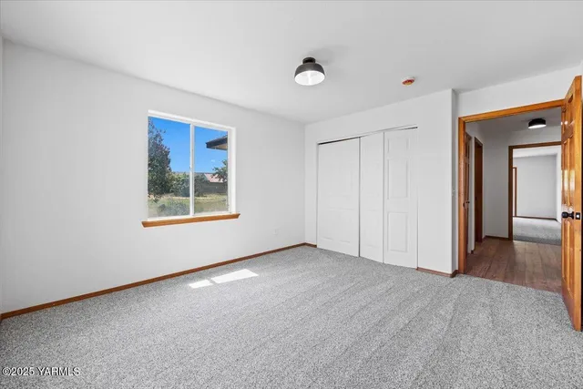 a view of an empty room with window and closet area