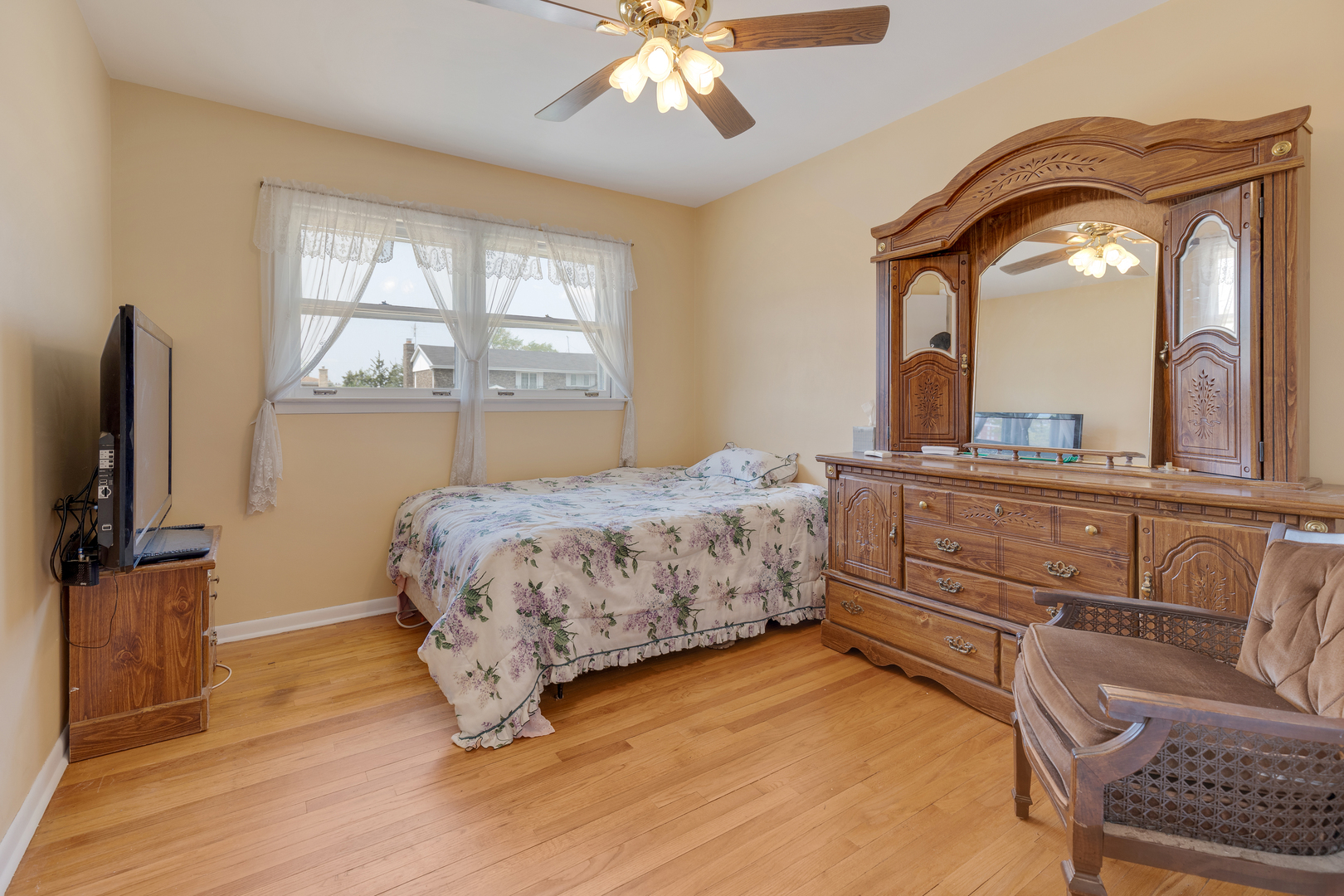 9363 Clancy Drive Des Plaines, IL 60016 - Photo 13 of 27 a bedroom with a large bed and a flat tv screen on dresser