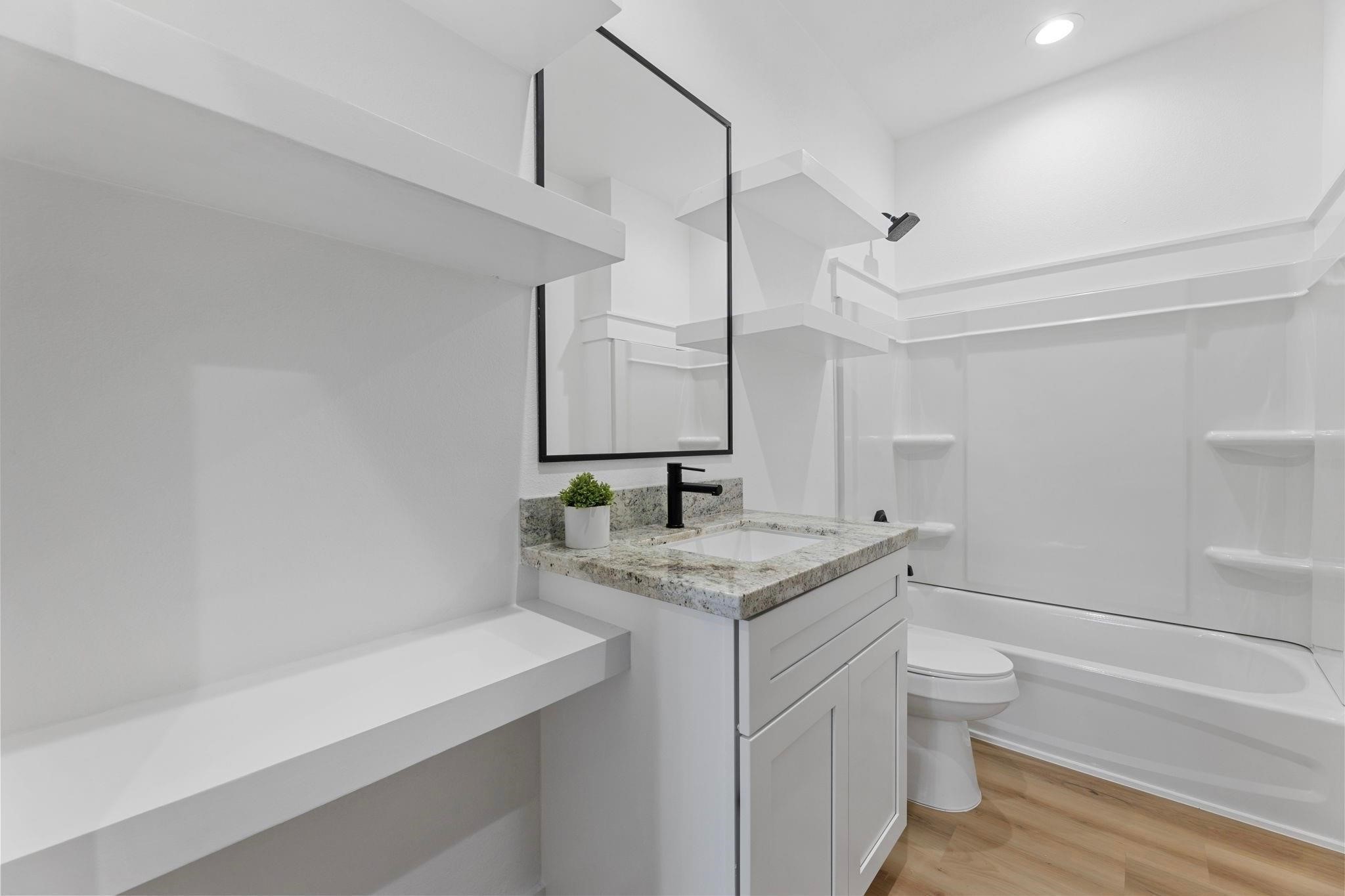 518 Clinton Street, Unit B Conroe, TX 77301 - Photo 39 of 50 a bathroom with a granite countertop sink a toilet and a bathtub