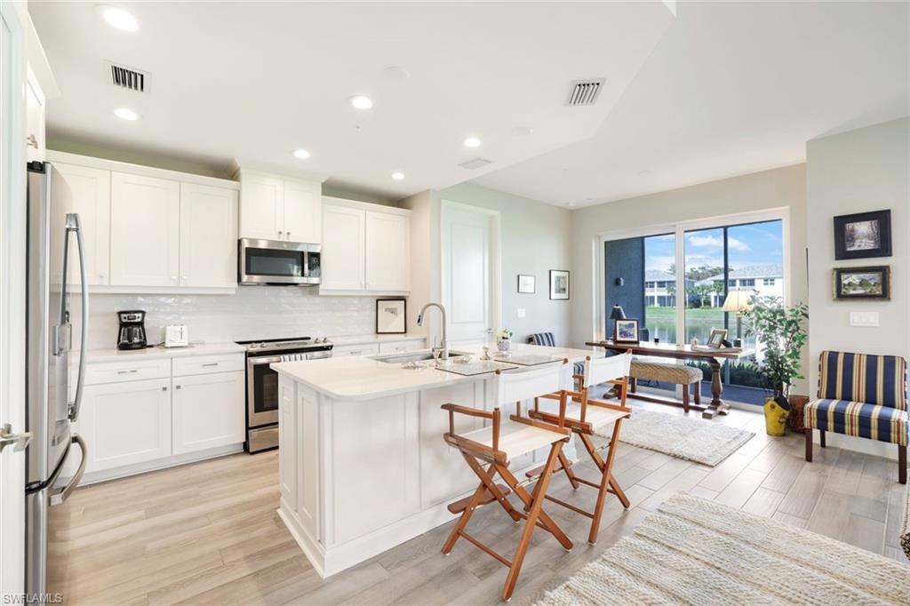 2647 Seychelles Circle, Unit 2204 Naples, FL 34112 - Photo 7 of 29 a view of kitchen with cabinets and wooden floor