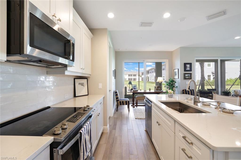 2647 Seychelles Circle, Unit 2204 Naples, FL 34112 - Photo 9 of 29 a kitchen with stainless steel appliances a stove a sink a microwave a stove and white cabinets