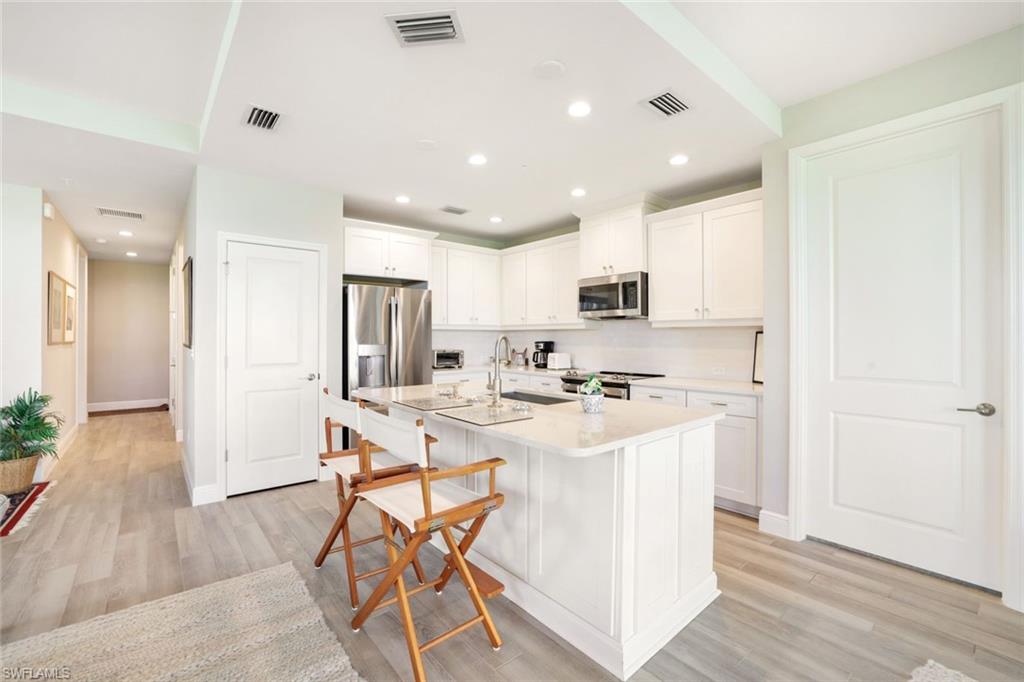 2647 Seychelles Circle, Unit 2204 Naples, FL 34112 - Photo 10 of 29 a kitchen with a sink a refrigerator and wooden floor