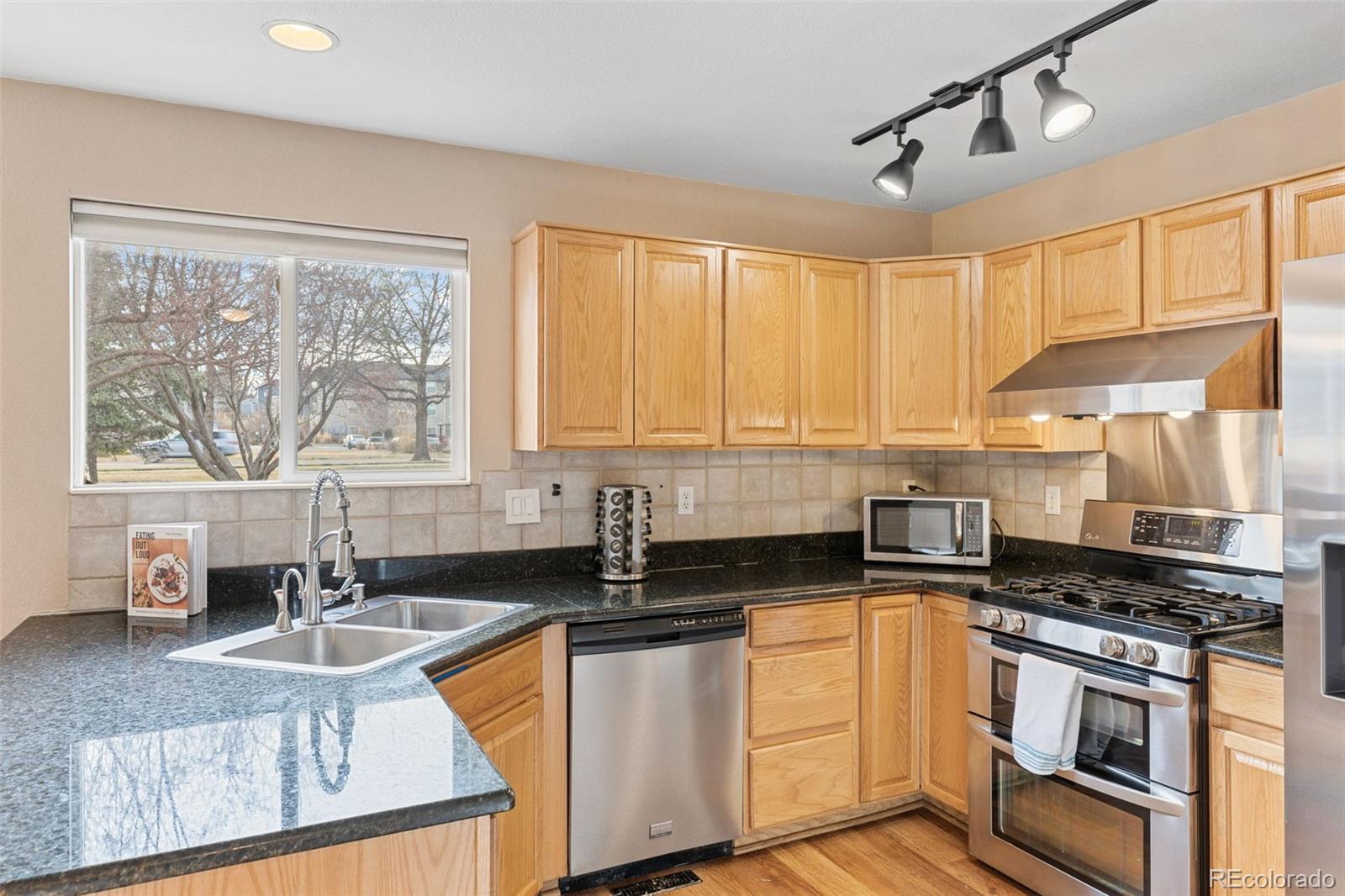 1189 Fall River Circle Longmont, CO 80504 - Photo 14 of 46 a kitchen with stainless steel appliances granite countertop a sink a stove cabinets counter space and a window