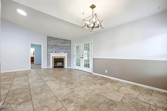 a view of an empty room with chandelier fan and fire place