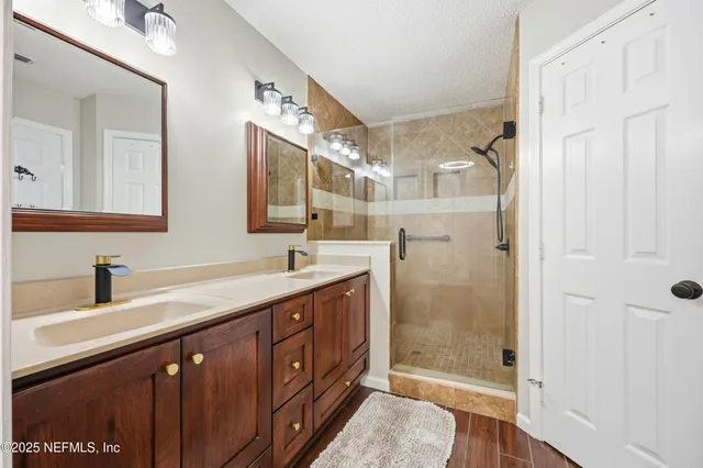 a bathroom with a double vanity sink mirror and shower