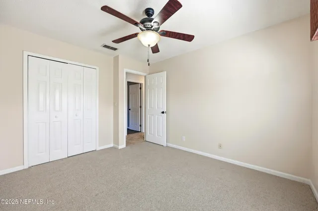 an empty room with a ceiling fan and a window
