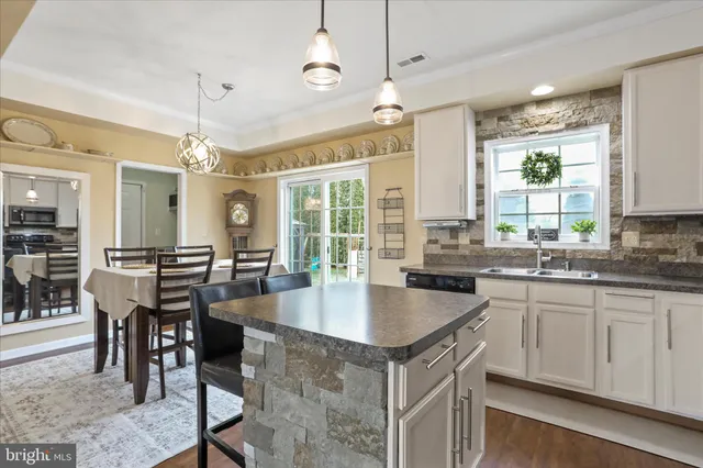 a kitchen with granite countertop a table chairs sink and cabinets