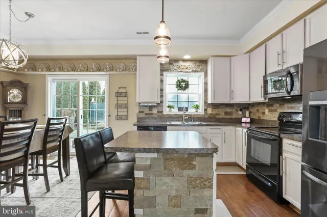 a kitchen with stainless steel appliances granite countertop a stove a sink dishwasher a dining table and chairs with wooden floor