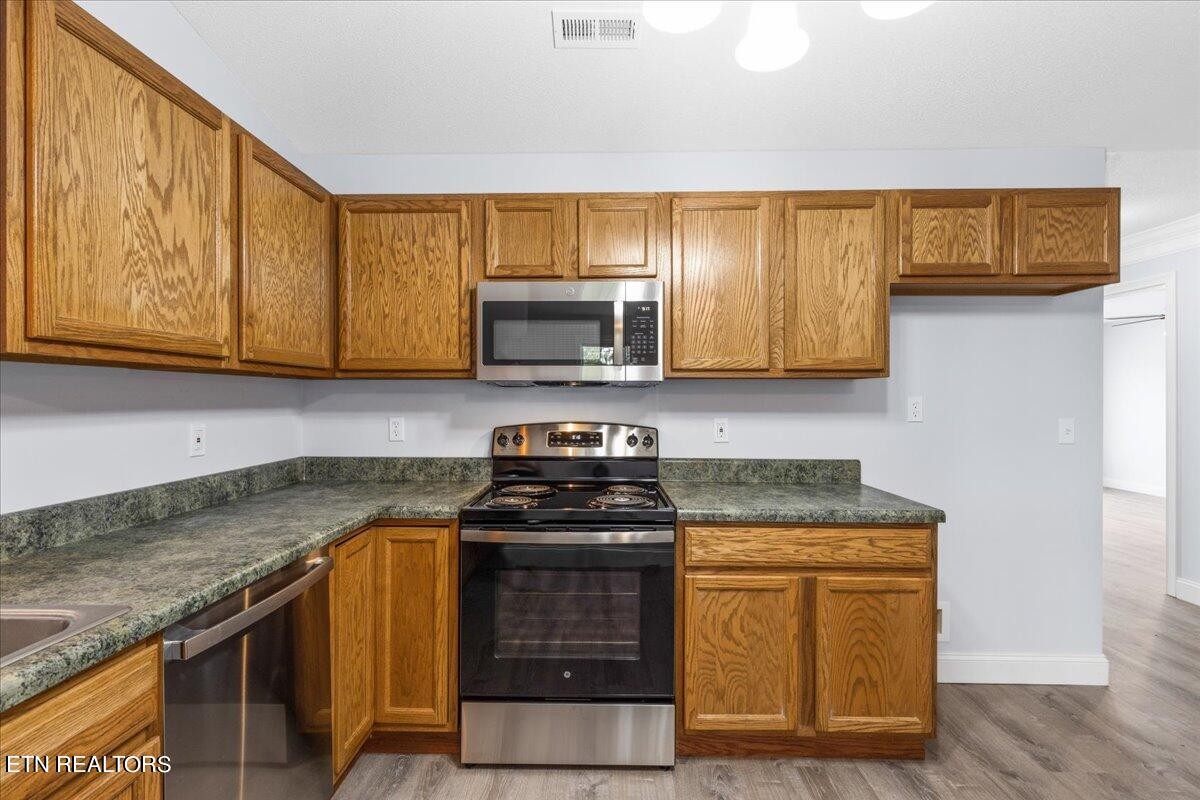 731 High Point Way, Knoxville, TN 37912 - Photo 13 of 25 a kitchen with stainless steel appliances granite countertop a stove a microwave and wooden cabinets
