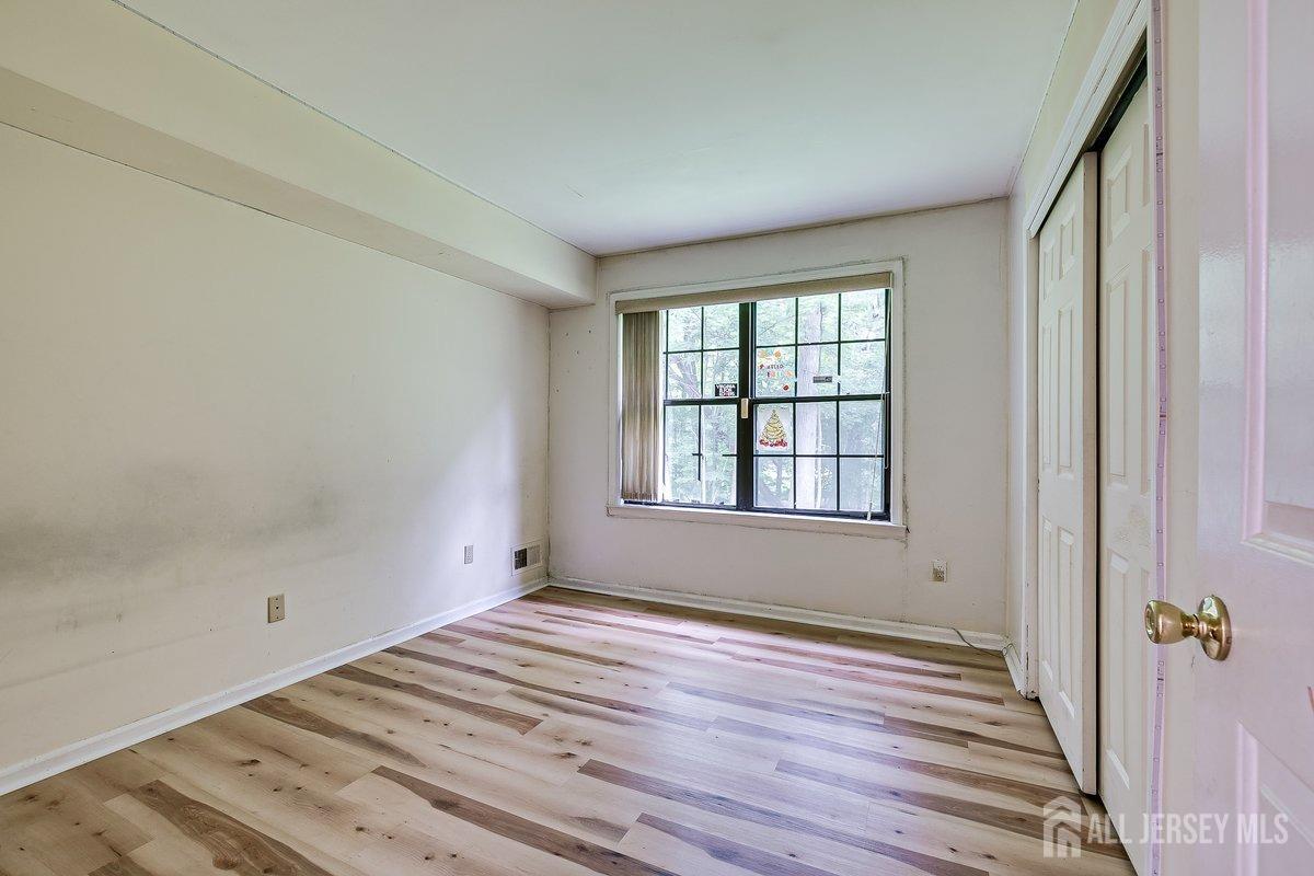 5001 Stonehedge Road Edison, NJ 08820 - Photo 18 of 22 a view of an empty room with wooden floor and a window