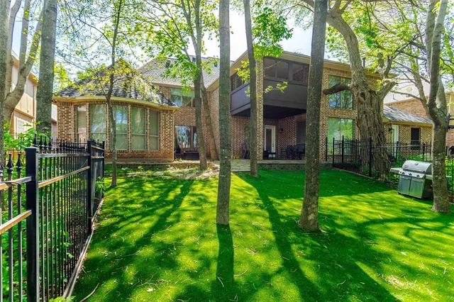 a view of a brick house with a big yard and plants