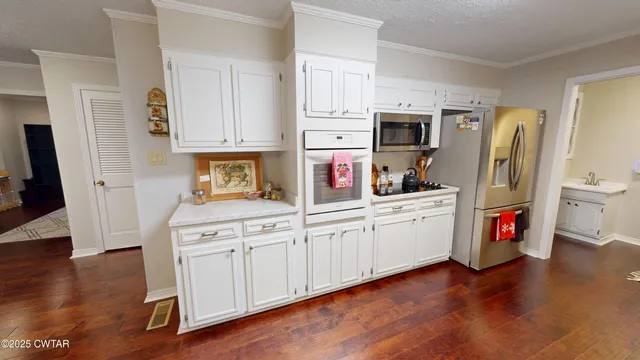 a kitchen with stainless steel appliances a stove top oven a sink a dining table and chairs with wooden floor