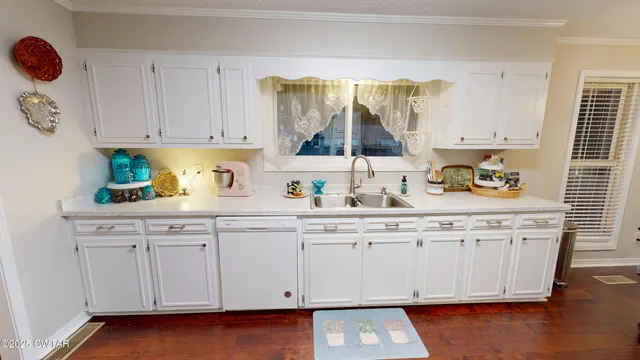 a kitchen with stainless steel appliances a refrigerator a sink and white cabinets with wooden floor