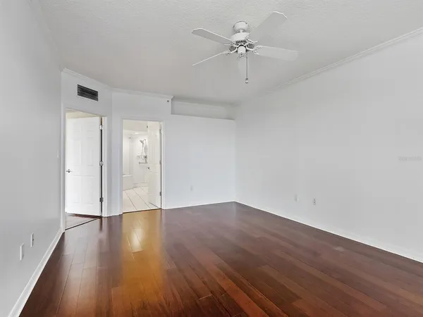 an empty room with wooden floor and ceiling fan