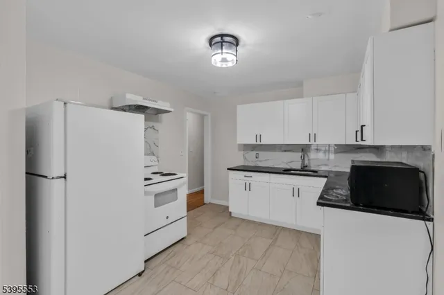 a kitchen with granite countertop a refrigerator stove and sink