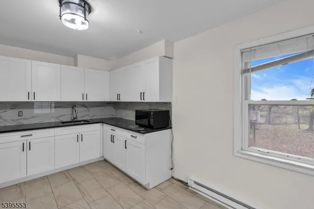 a kitchen with granite countertop white cabinets and a window