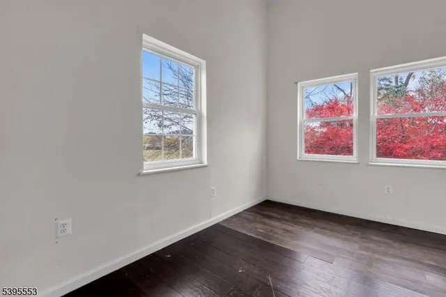 a view of an empty room with wooden floor and window