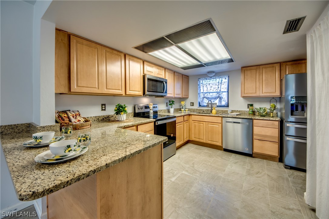 a kitchen with stainless steel appliances granite countertop a sink dishwasher stove top oven and cabinets