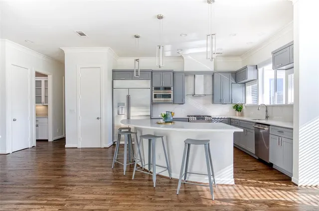 a kitchen with stainless steel appliances granite countertop a table chairs wooden floors a large window and white cabinets