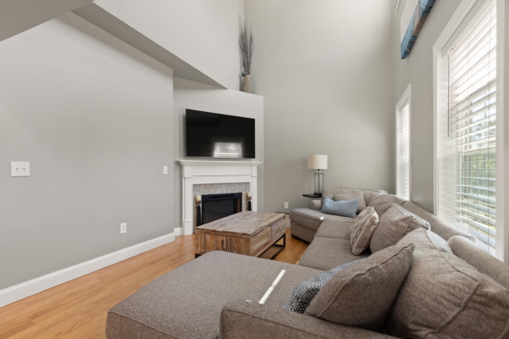 284 Maple Street, Unit 284 Middleton, MA 01949 - Photo 6 of 30 a living room with furniture a fireplace and a flat screen tv