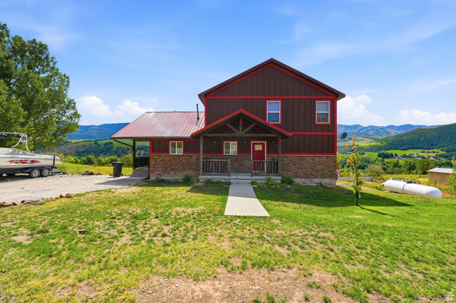 306 Spring Road Preston, ID 83263 - Photo 52 of 55 Two-story residence featuring a brown siding exterior with red trim, a red metal roof, and stone facade accents