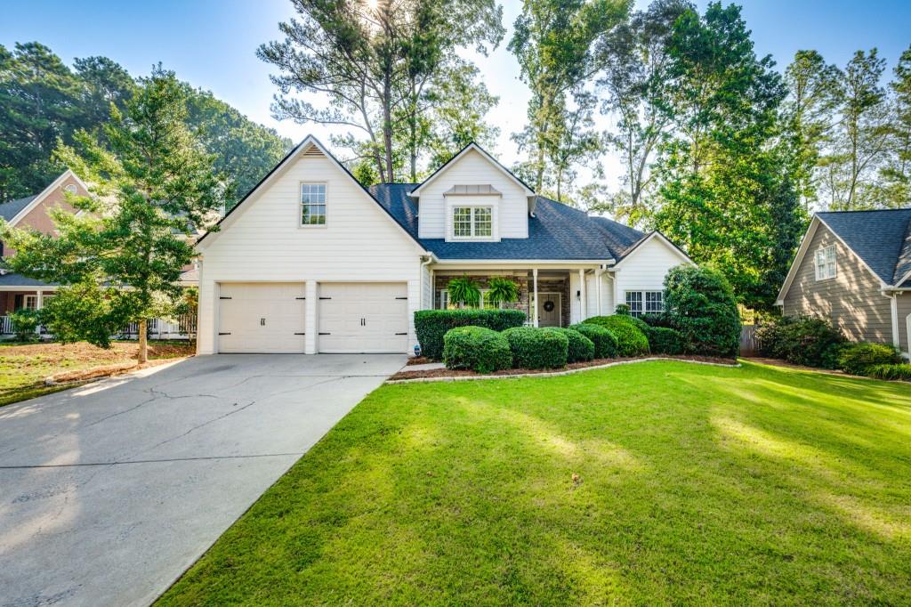 a view of a yard in front of a house with plants and large trees