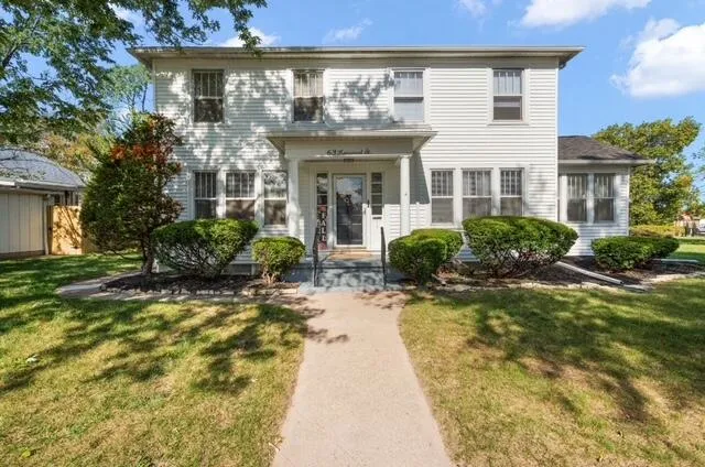 a front view of a house with a yard and potted plants