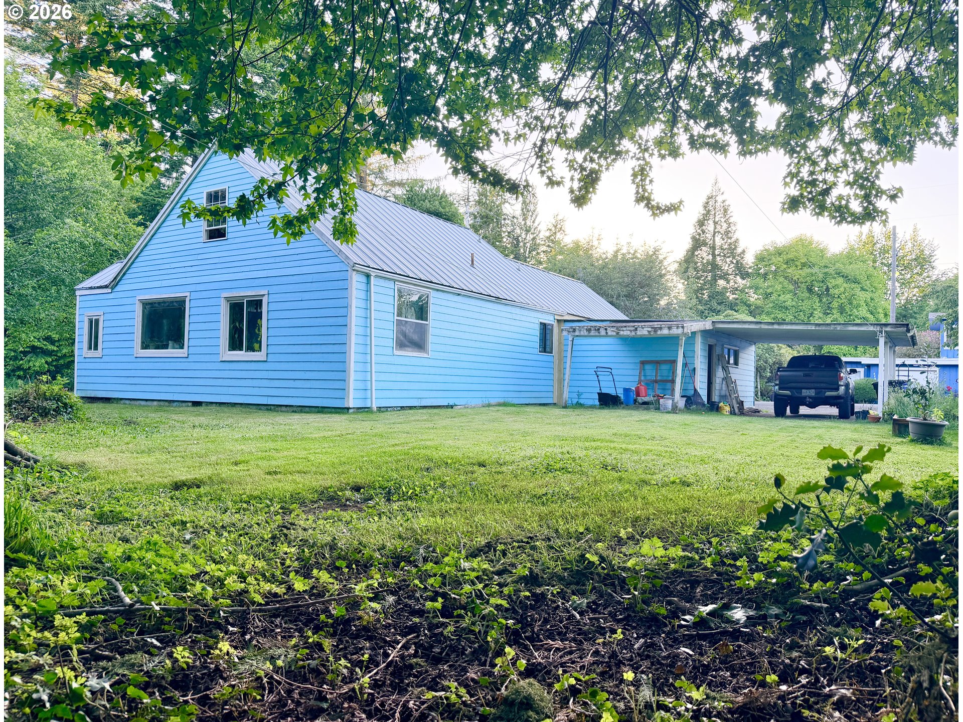 677 Southeast Moffitt Road Waldport, OR 97394 - Photo 3 of 36 a brick house with a yard plants and large tree