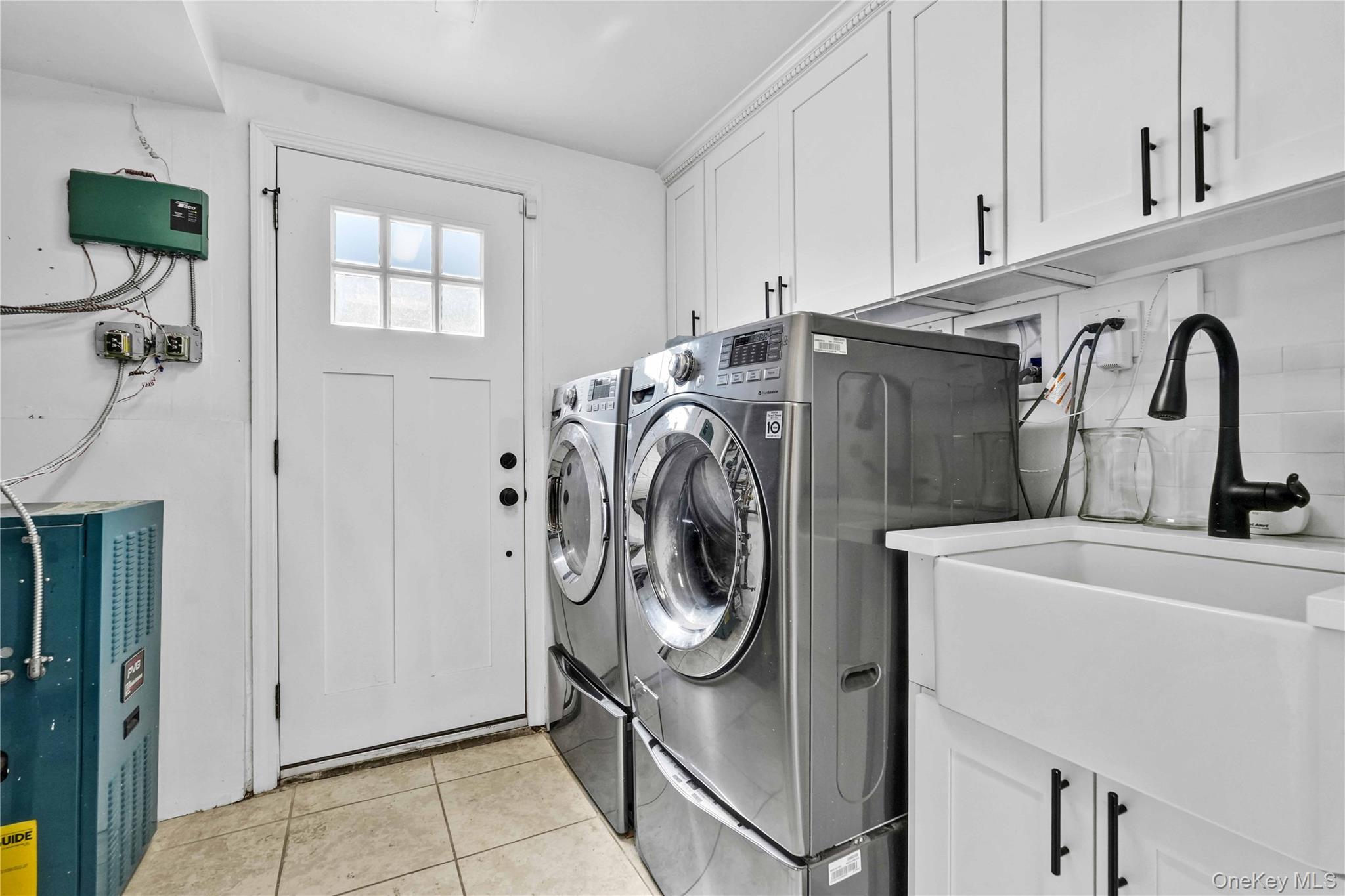 2 Amherst Lane Smithtown, NY 11787 - Photo 24 of 33 Washroom featuring cabinet space, light tile patterned flooring, and washing machine and dryer