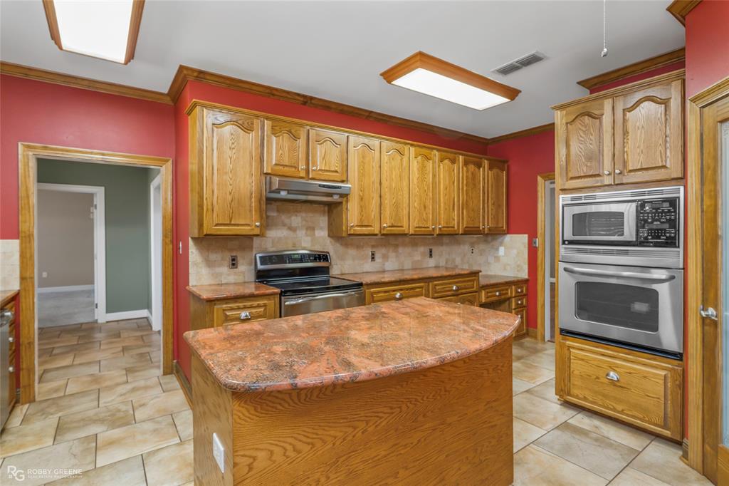 703 Airport Loop Homer, LA 71040 - Photo 9 of 32 a kitchen with stainless steel appliances granite countertop a stove a sink and a microwave