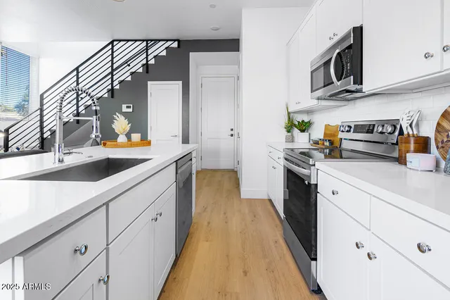 a kitchen with stainless steel appliances a sink a stove and white cabinets