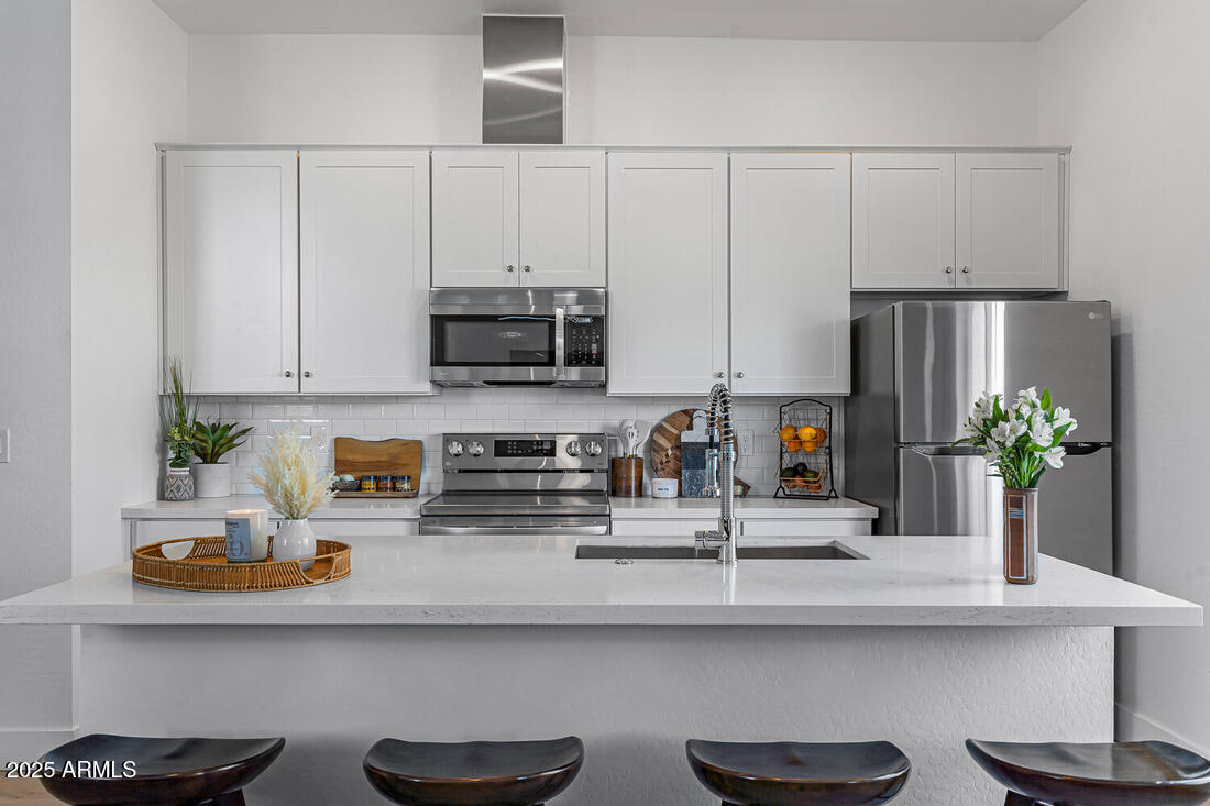 1247 East Colter Street, Unit 1 Phoenix, AZ 85014 - Photo 9 of 32 a kitchen with stainless steel appliances a sink a stove and white cabinets