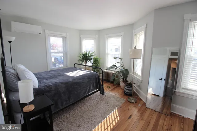 a bedroom with a bed a large window and wooden floor