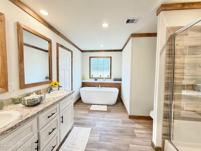 a spacious bathroom with a double vanity sink a mirror and a bathtub