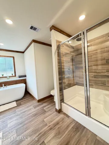 a view of an empty room with wooden floor and windows