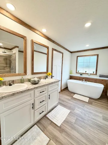 a spacious bedroom with a double vanity sink mirror and bathtub