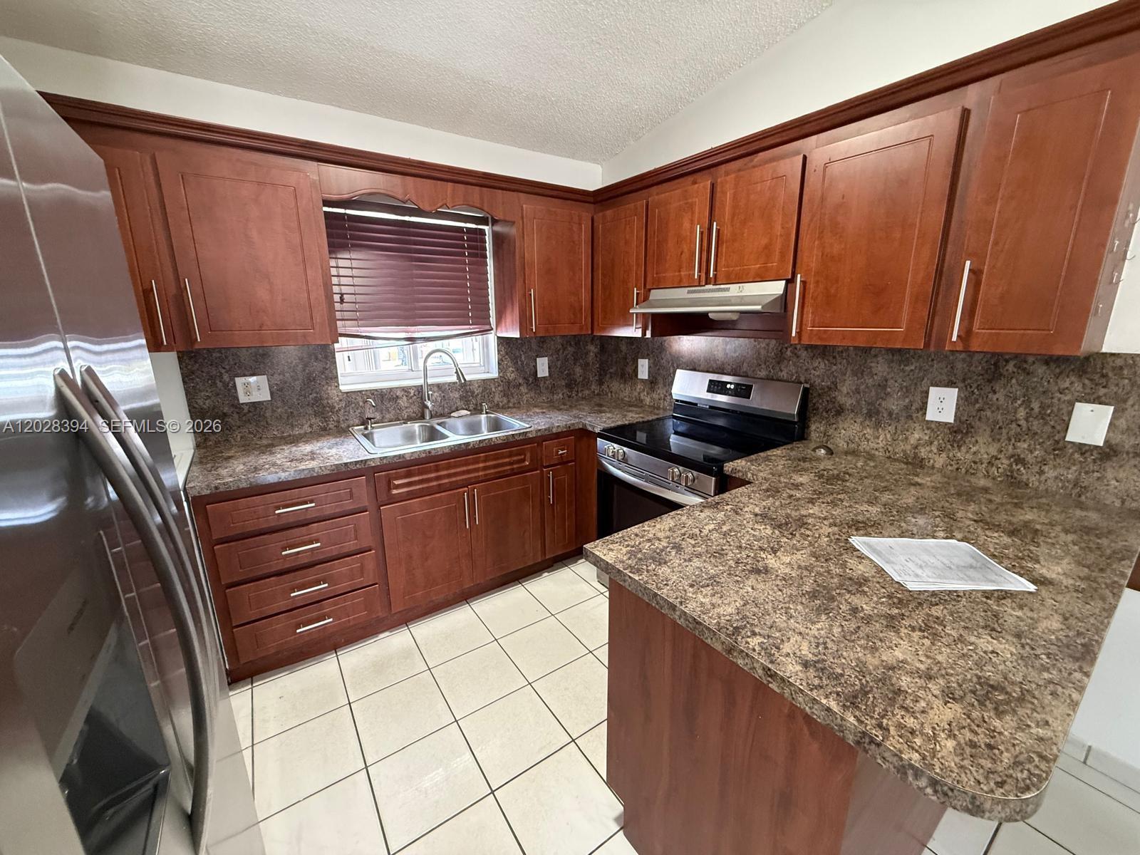 2212 West 74th Street, Unit 20128 Hialeah, FL 33016 - Photo 2 of 11 a kitchen with granite countertop wooden cabinets and white appliances