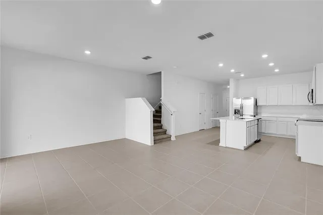 a view of kitchen with refrigerator and white cabinets