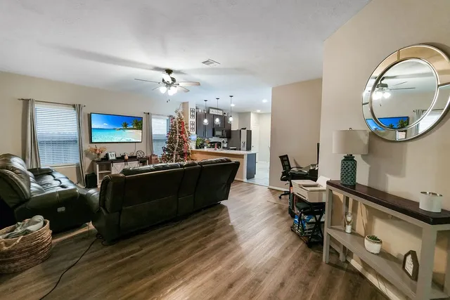 a living room with furniture a mirror and a wooden floor